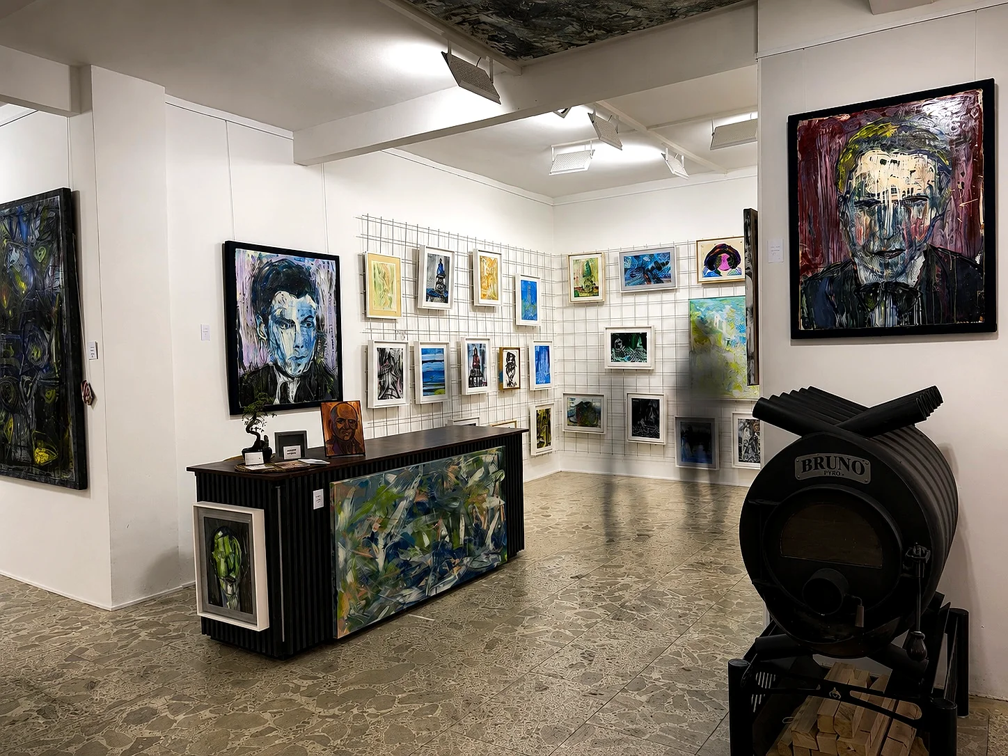 Empfangsbereich der Galerie Kant-ART mit Kleinformaten und Ofen